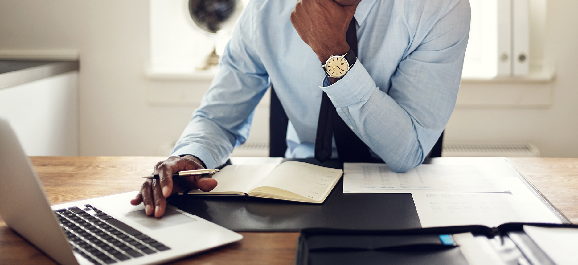 Attorney working at desk with laptop and paperwork in front of him